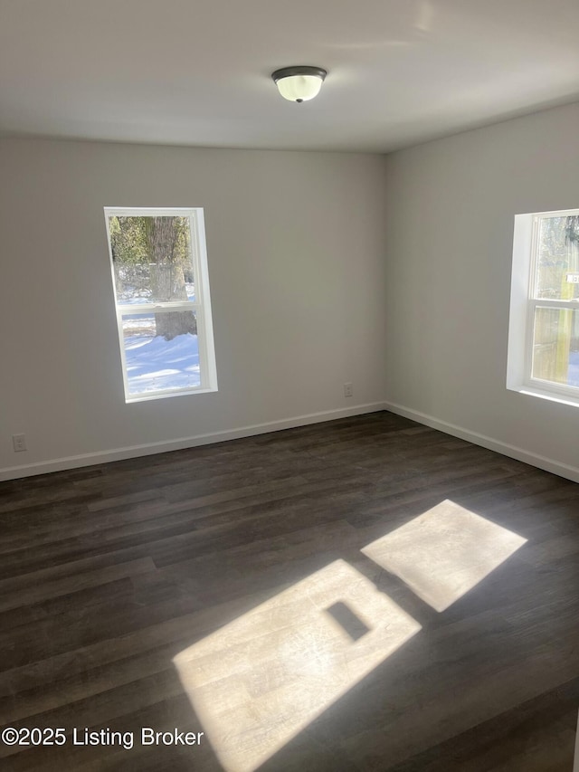 spare room featuring a healthy amount of sunlight and dark hardwood / wood-style floors