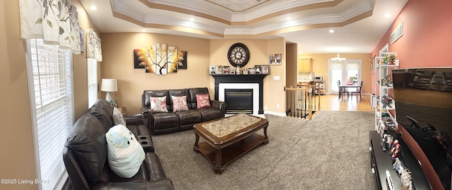 living room with a raised ceiling, crown molding, and carpet floors