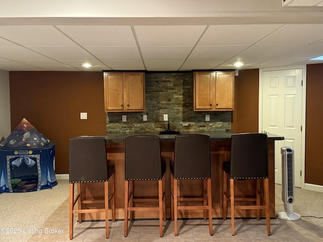 bar featuring a drop ceiling and backsplash