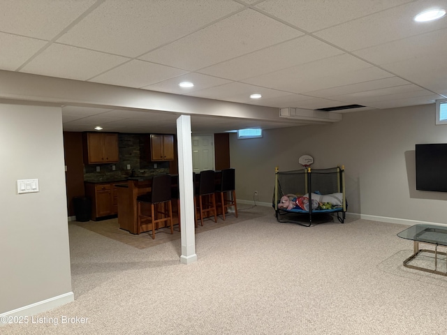 living room with light carpet, a paneled ceiling, and indoor bar