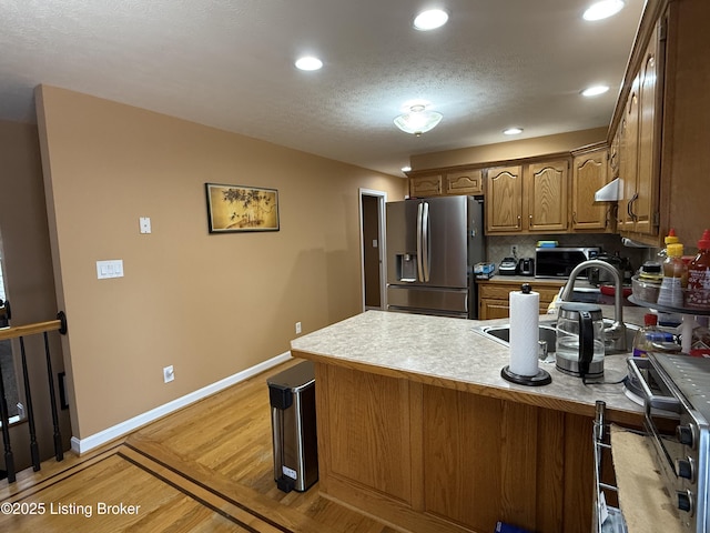 kitchen with extractor fan, stainless steel fridge, decorative backsplash, kitchen peninsula, and light hardwood / wood-style flooring