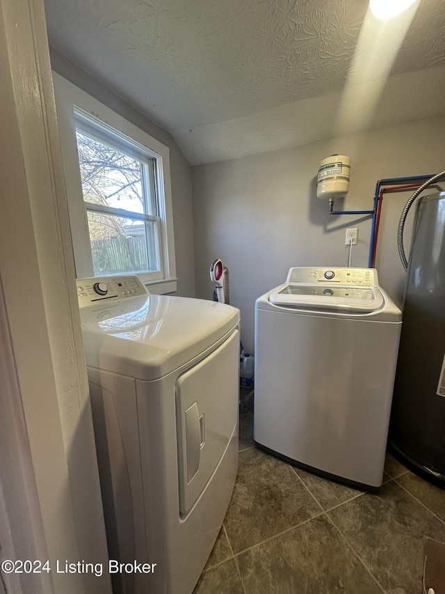 laundry area with a textured ceiling, dark tile patterned floors, water heater, and washing machine and clothes dryer