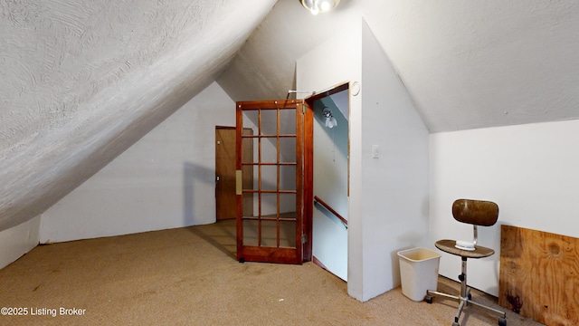 additional living space with light carpet, vaulted ceiling, and a textured ceiling