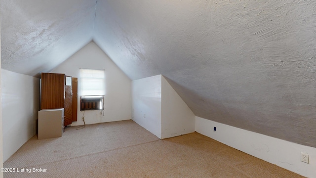 bonus room with lofted ceiling, light colored carpet, and a textured ceiling