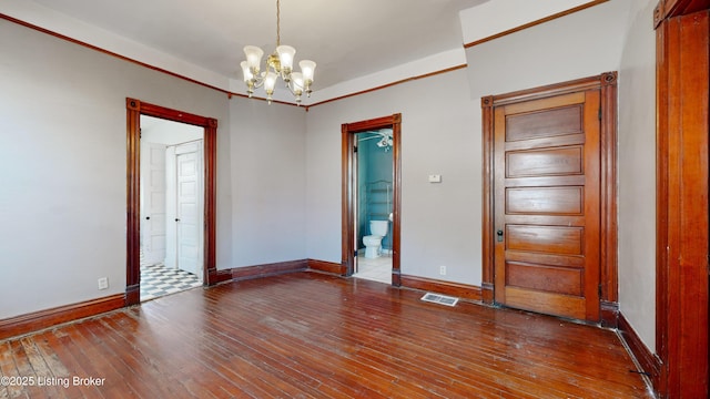 unfurnished room featuring wood-type flooring and a notable chandelier