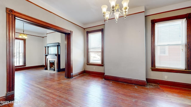 empty room featuring wood-type flooring and a chandelier