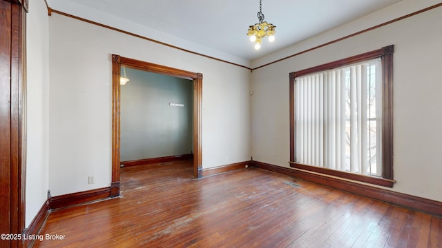 spare room with an inviting chandelier and hardwood / wood-style flooring