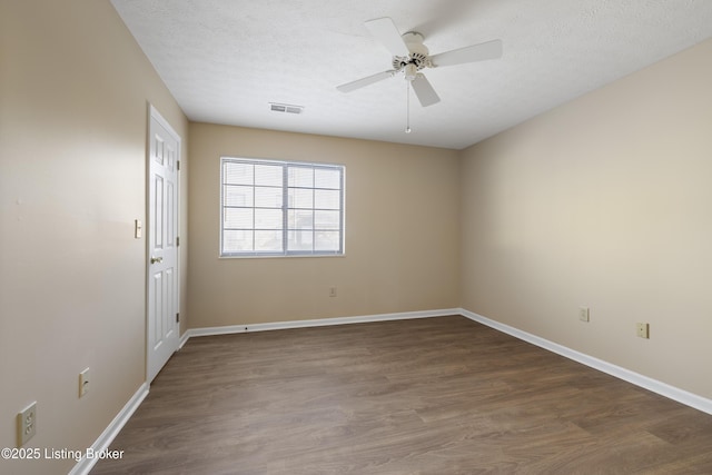 spare room featuring ceiling fan, dark wood-type flooring, and a textured ceiling