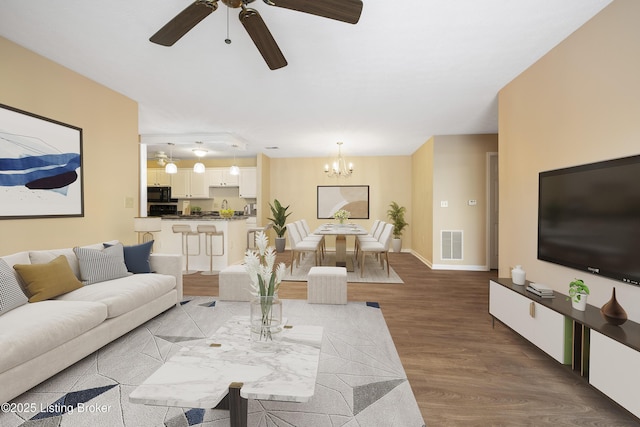 living room with ceiling fan with notable chandelier and wood-type flooring