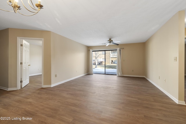 empty room featuring ceiling fan with notable chandelier and dark wood-type flooring