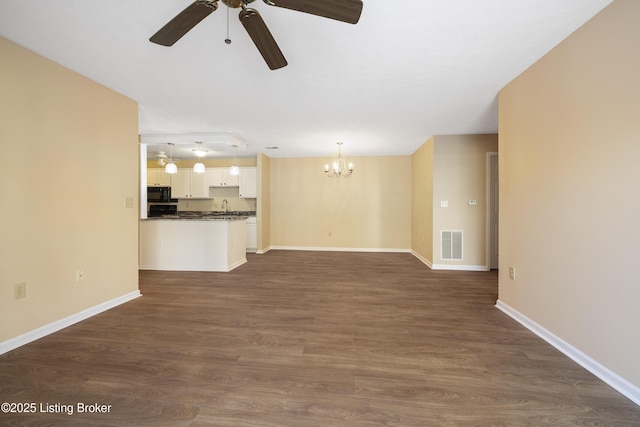 unfurnished living room with sink, ceiling fan with notable chandelier, and dark wood-type flooring