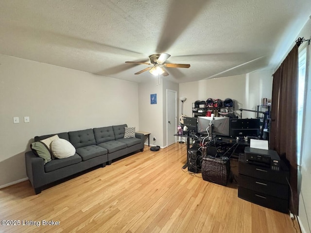 living room with ceiling fan, light hardwood / wood-style flooring, and a textured ceiling