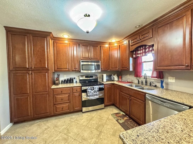 kitchen featuring sink, light stone counters, a textured ceiling, light tile patterned floors, and stainless steel appliances