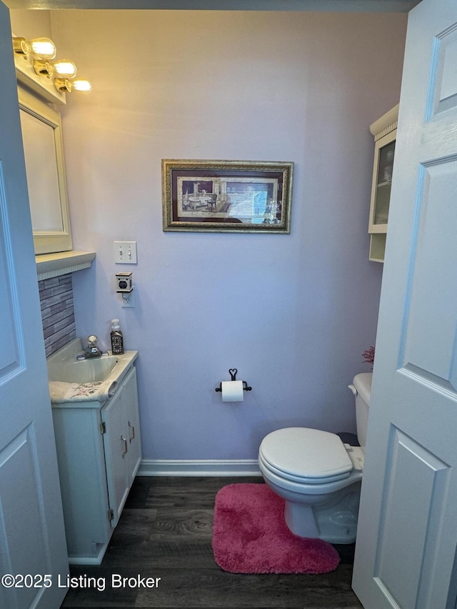 bathroom featuring tasteful backsplash, vanity, wood-type flooring, and toilet