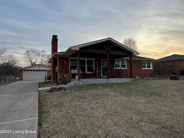 view of front of home with a garage, a yard, an outbuilding, and covered porch