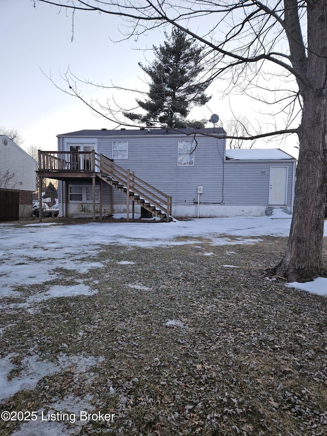 snow covered rear of property with a wooden deck