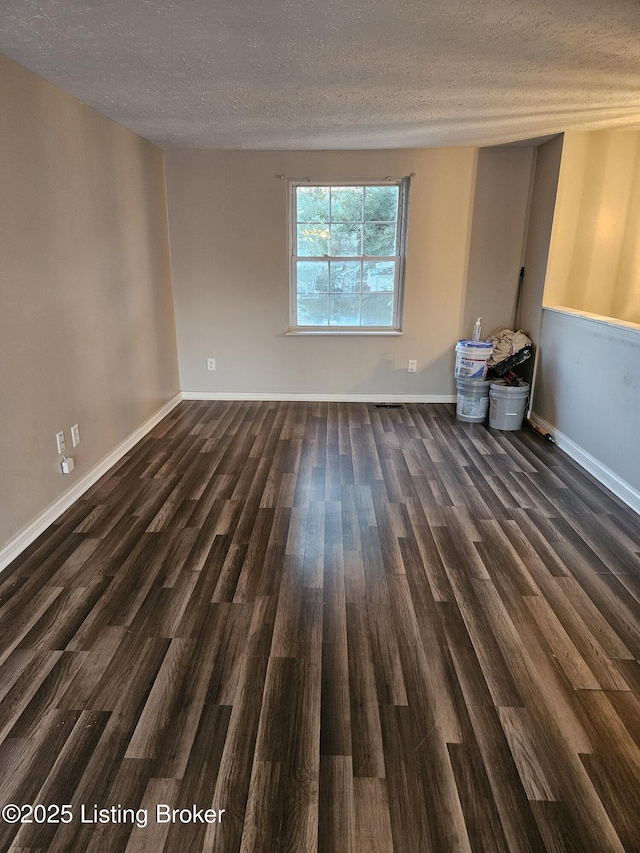 unfurnished room featuring dark hardwood / wood-style flooring and a textured ceiling