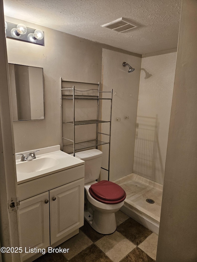 bathroom featuring vanity, toilet, a textured ceiling, and a shower