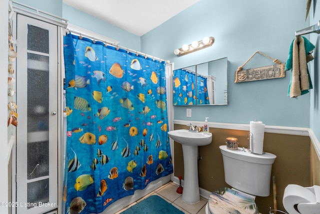 bathroom featuring toilet, tile patterned floors, and a shower with curtain