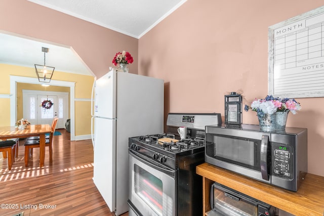 kitchen featuring pendant lighting, ornamental molding, stainless steel appliances, and wood-type flooring