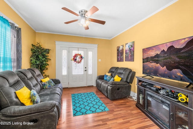 living room with wood-type flooring, ornamental molding, and ceiling fan