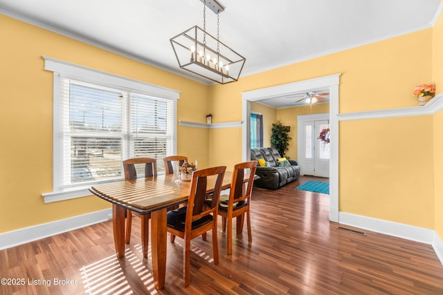 dining area with hardwood / wood-style floors, a notable chandelier, and ornamental molding