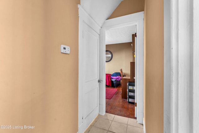 hallway featuring lofted ceiling and light tile patterned floors