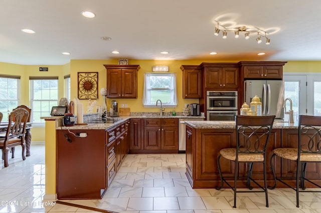 kitchen featuring sink, a breakfast bar area, light stone counters, a center island, and stainless steel appliances