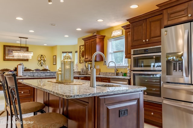 kitchen with a breakfast bar area, light stone counters, decorative light fixtures, a center island, and appliances with stainless steel finishes