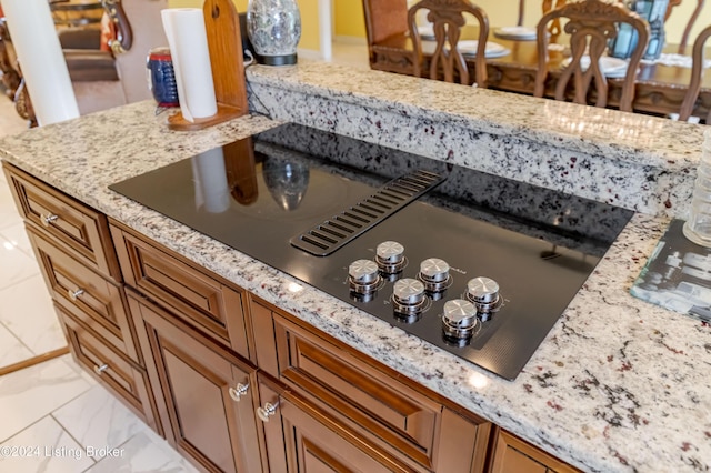 interior details with light stone counters and black electric cooktop