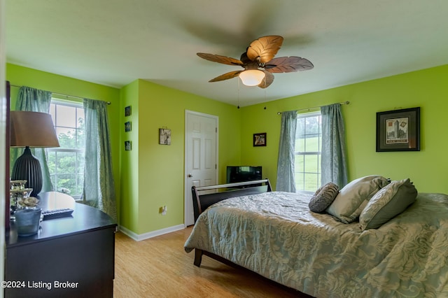 bedroom with ceiling fan, light hardwood / wood-style floors, and multiple windows