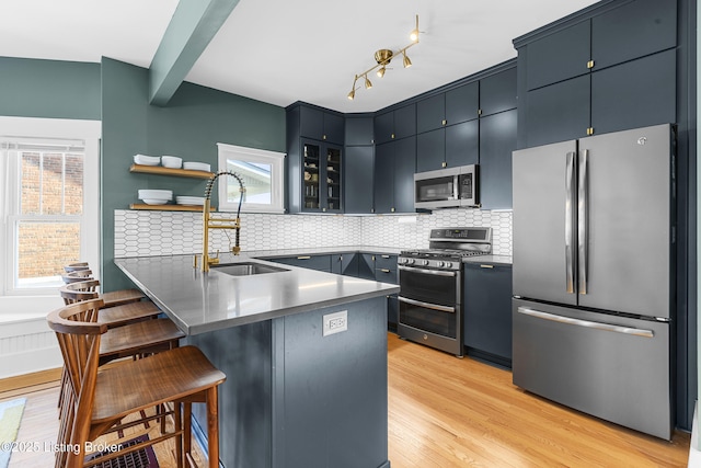 kitchen featuring sink, a kitchen bar, decorative backsplash, light hardwood / wood-style floors, and stainless steel appliances