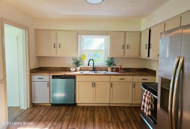 kitchen featuring dark hardwood / wood-style floors, sink, stainless steel appliances, a textured ceiling, and cream cabinetry