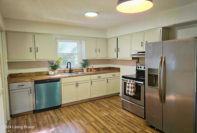 kitchen with stainless steel appliances, sink, wooden counters, and light wood-type flooring