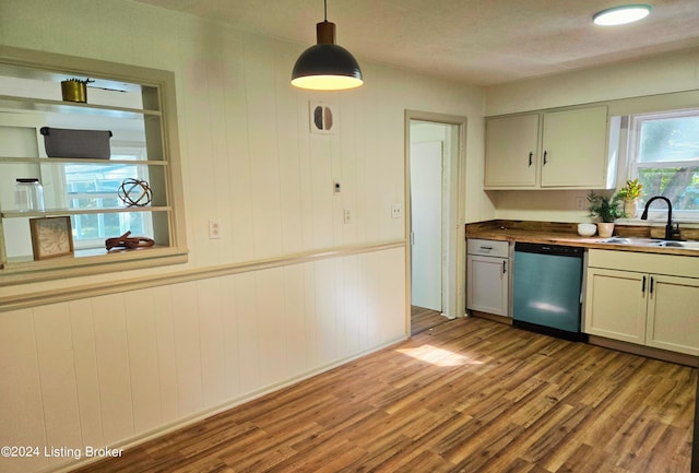 kitchen with sink, butcher block counters, light hardwood / wood-style floors, decorative light fixtures, and stainless steel dishwasher