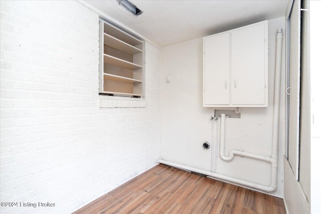 washroom with cabinets, brick wall, and hardwood / wood-style flooring