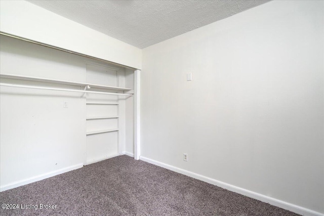 unfurnished bedroom featuring carpet, a textured ceiling, and a closet