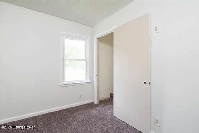 carpeted empty room featuring a textured ceiling