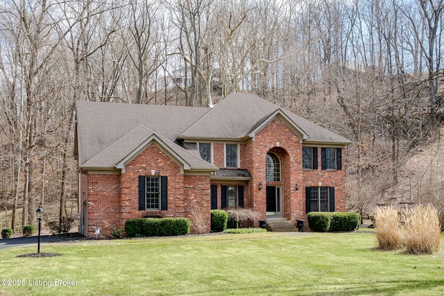 view of front of house featuring brick siding, a front yard, and a shingled roof