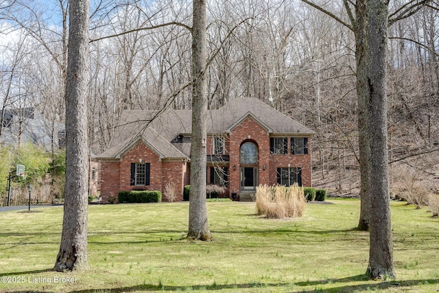 view of front facade with a shingled roof, brick siding, and a front lawn