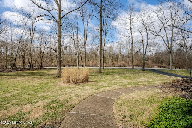 view of property's community with a lawn and fence