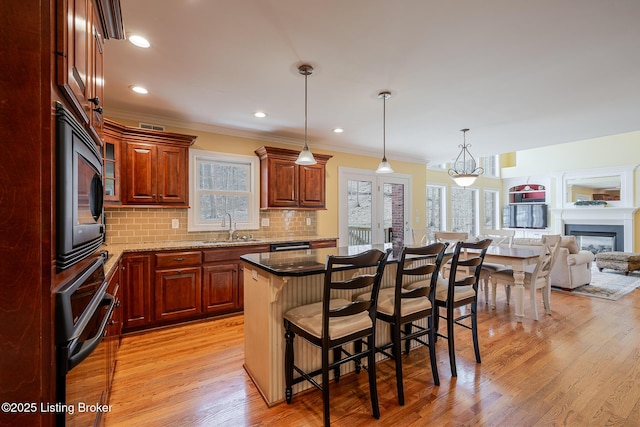 kitchen featuring decorative backsplash, wall oven, a sink, black microwave, and a kitchen breakfast bar