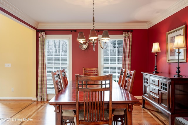 dining space with ornamental molding, a notable chandelier, baseboards, and wood finished floors