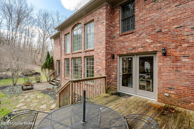 rear view of house with outdoor dining space, a patio area, an outdoor fire pit, and brick siding