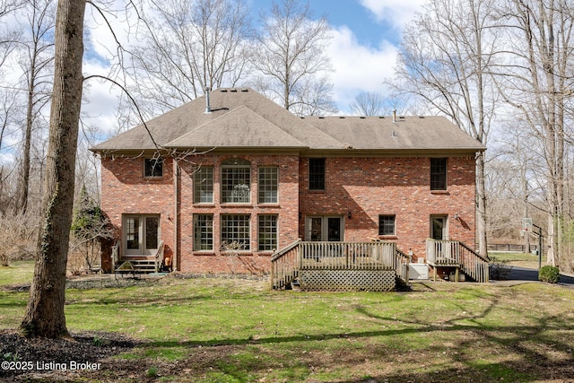 rear view of house featuring a yard, brick siding, roof with shingles, and a wooden deck