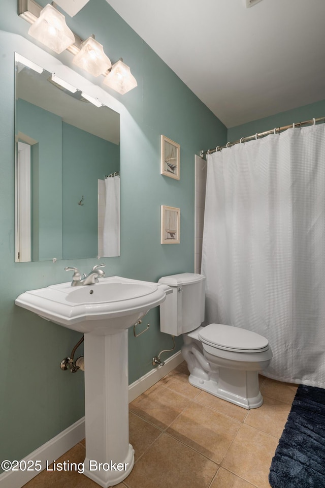 bathroom featuring baseboards, a sink, toilet, and tile patterned floors