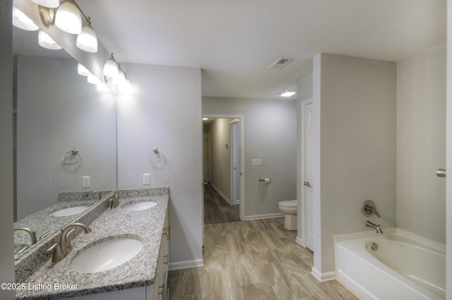 bathroom with vanity, wood-type flooring, a bath, and toilet