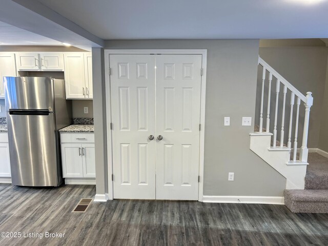 kitchen featuring dark hardwood / wood-style flooring, white cabinetry, light stone countertops, and stainless steel refrigerator