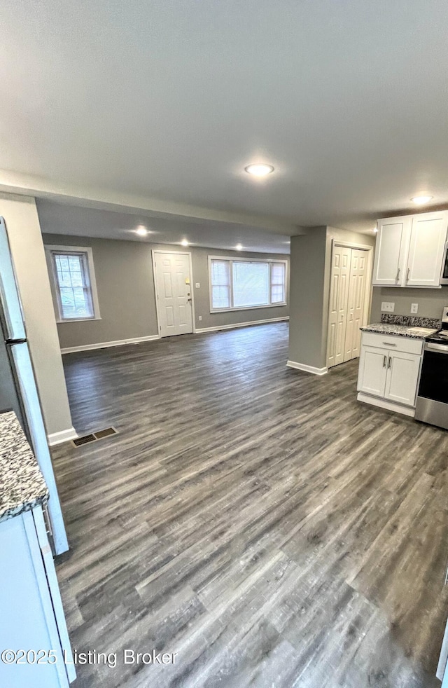 kitchen with electric stove, white cabinetry, dark hardwood / wood-style flooring, and dark stone countertops