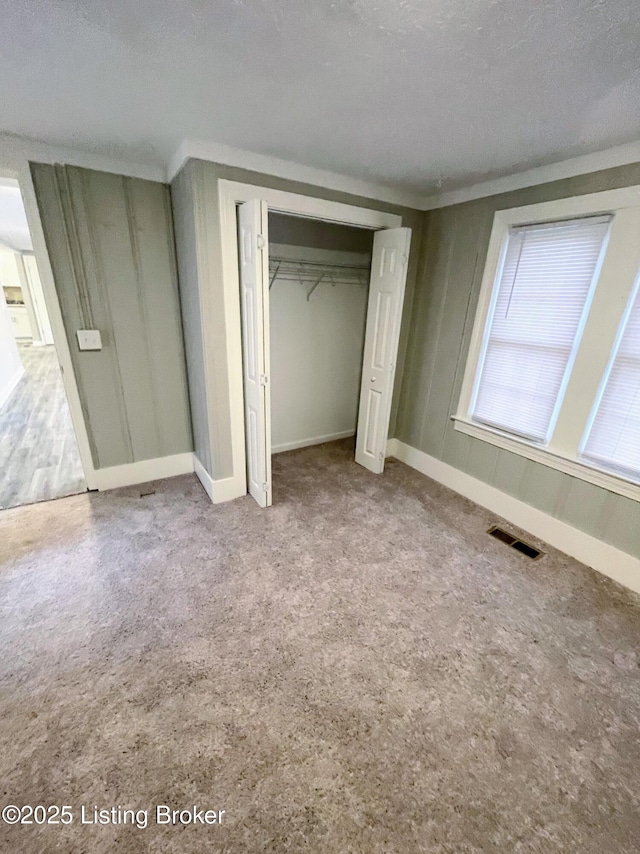 unfurnished bedroom with light colored carpet, a textured ceiling, and a closet